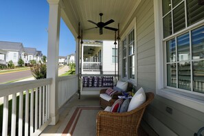 Eine überdachte Veranda mit Korbmöbeln und einem Deckenventilator.