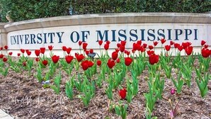 Een bord voor de Universiteit van Mississippi met rode tulpen ervoor.