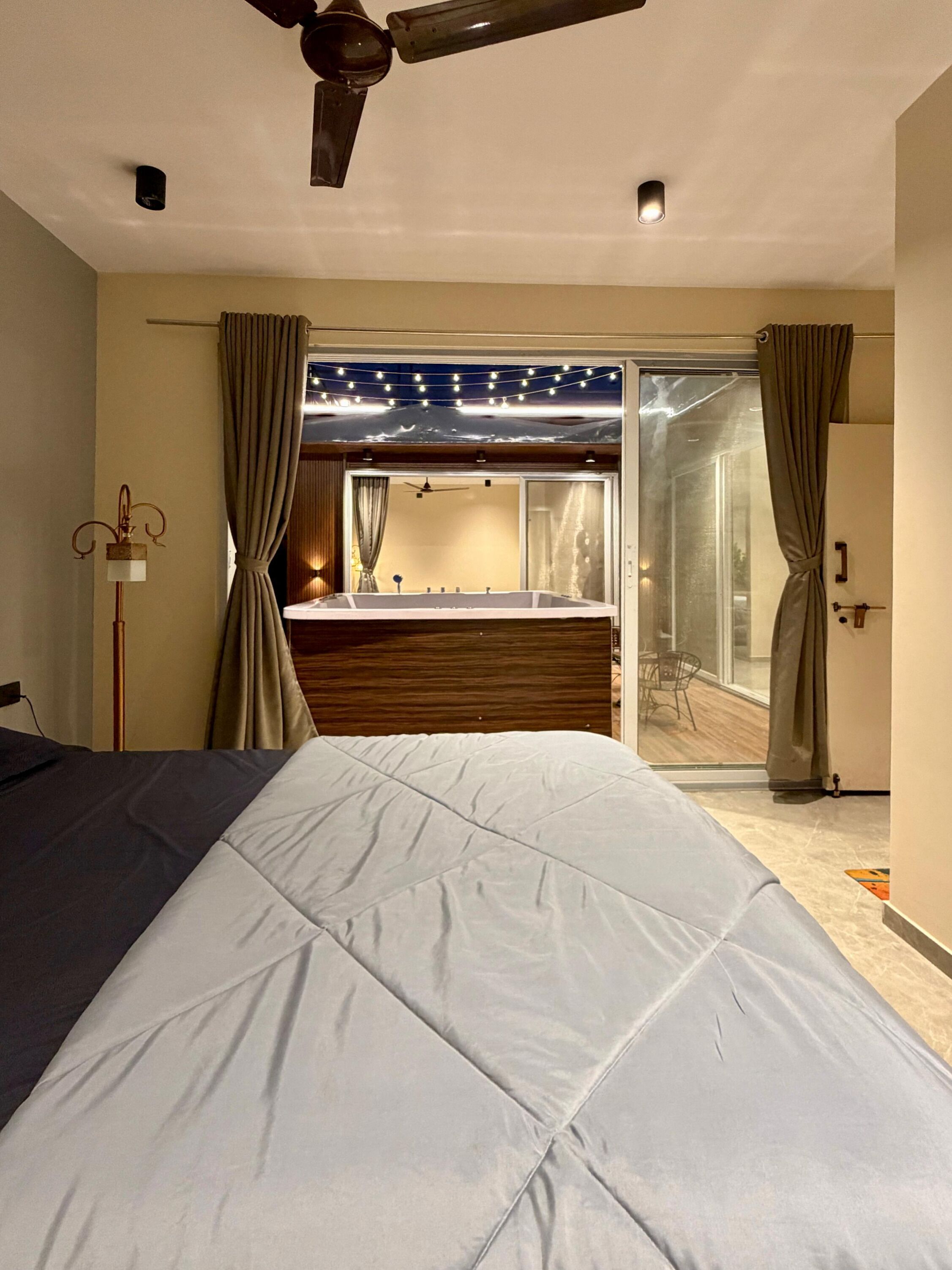 A bedroom with a bed, a ceiling fan, and a sliding glass door leading to a balcony.