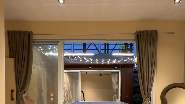 Un dormitorio con cama, ventilador de techo y vista a un balcón con cortinas.