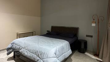 A bedroom with a bed, a ceiling fan, a floor lamp, and a bedside table.