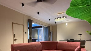 Una sala moderna con un sofá modular, dos mesas redondas de centro y un ventilador de techo.