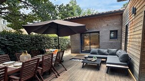 Eine Holzterrasse mit Essbereich, einer Sitzecke und einem Sonnenschirm.
