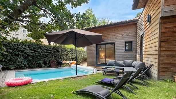Ein Garten mit Swimmingpool, Liegestühlen und einer Holzterrasse.