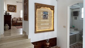 Eine Treppe führt zu einem Wohnbereich mit einer Couch, Dekorationselementen und einem gerahmten Bild an der Wand.