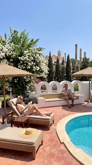 A poolside area with lounge chairs, a pool, and a view of ancient columns and a dome in the background. - celine 1 (Vernègues)