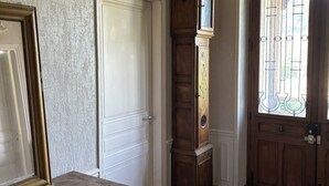 Un pasillo con un aparador de madera, un reloj de pie alto y una puerta con reja de metal.