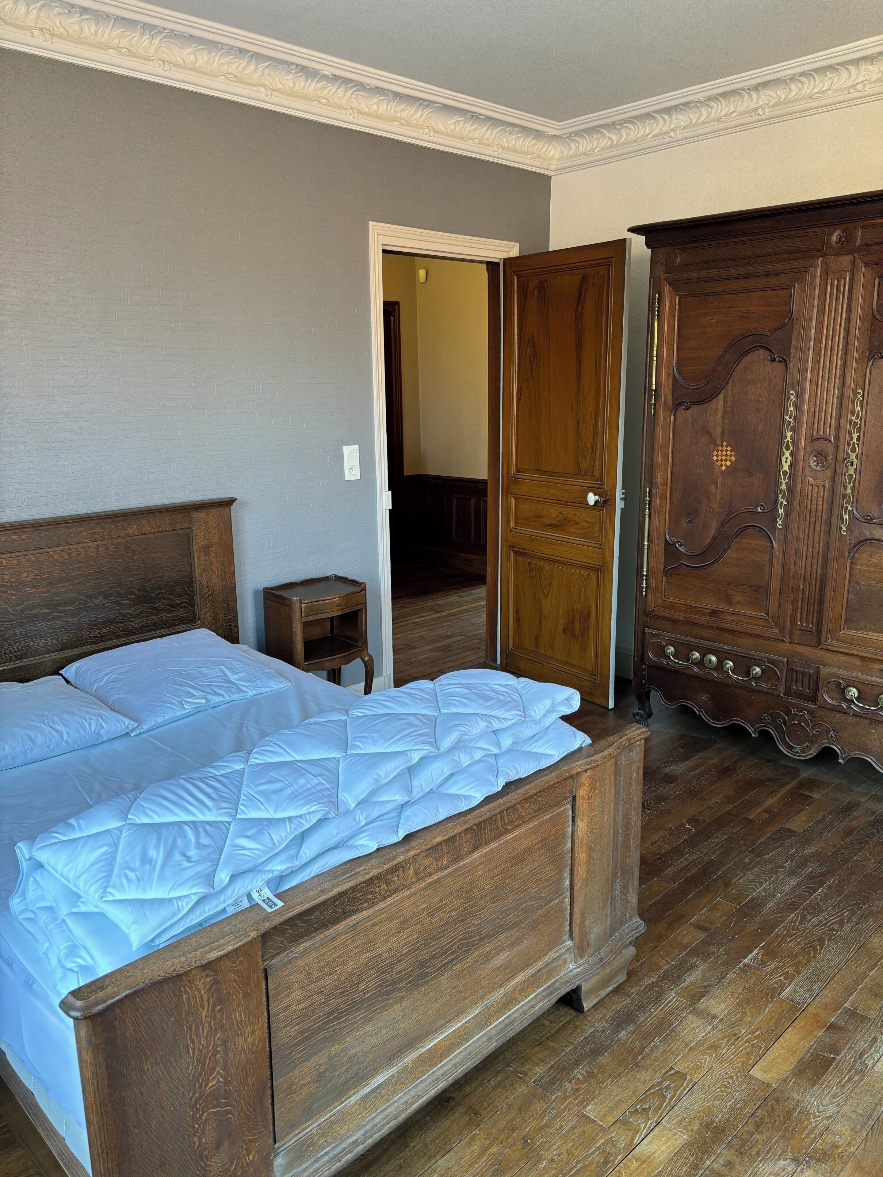 Een slaapkamer met een houten bed, een houten kast en een klein nachtkastje.