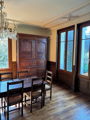 A dining room with a wooden table and chairs, a large wooden cabinet, and a chandelier.