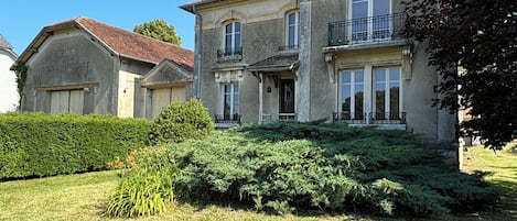 A large, two-story house with a symmetrical facade, multiple windows, and a well-maintained lawn.