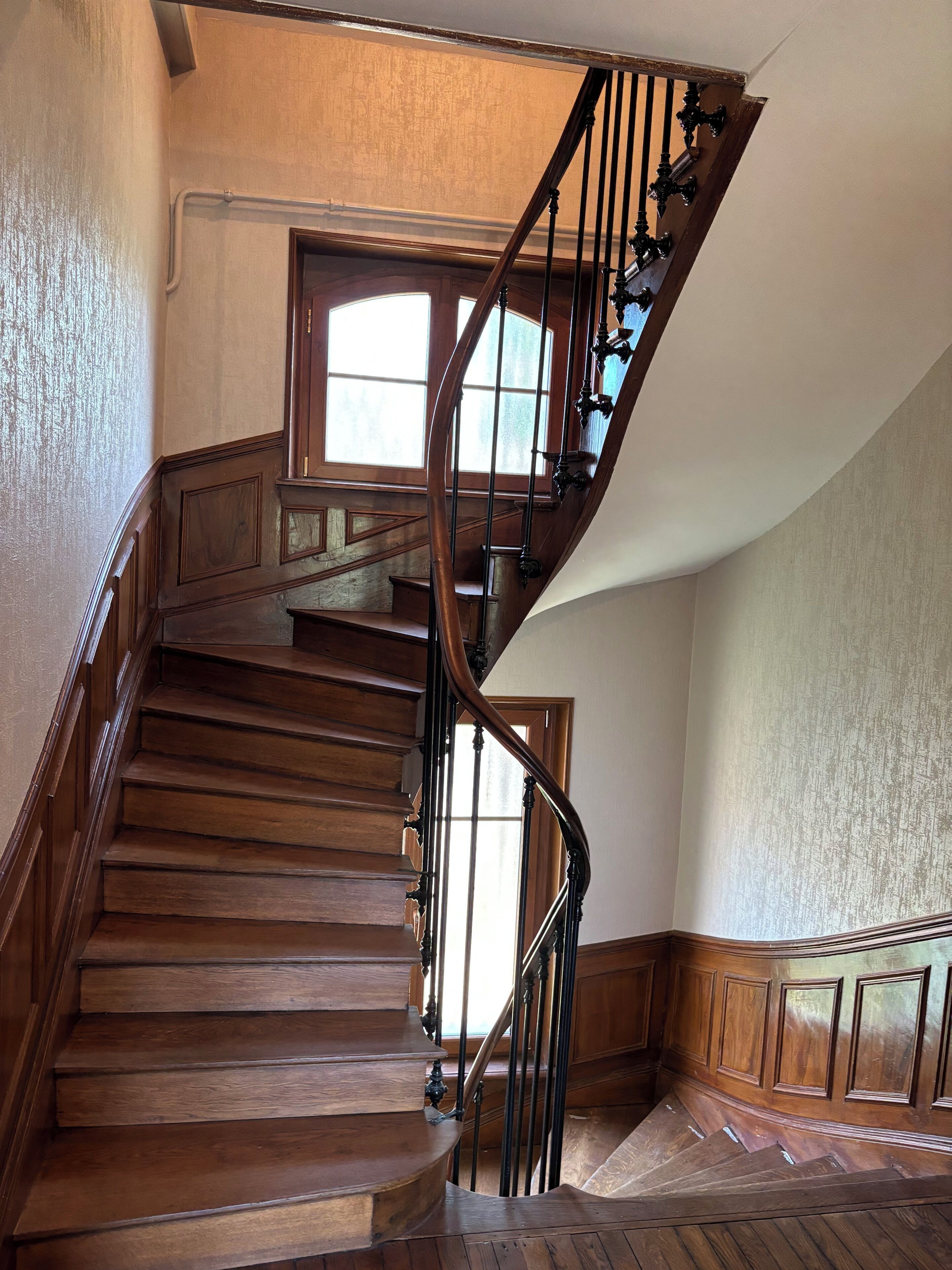 A wooden staircase with a curved design, leading to an upper floor.