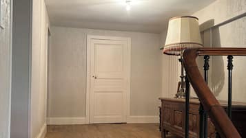 A wooden staircase with a lamp, a closed door, and a wooden floor.
