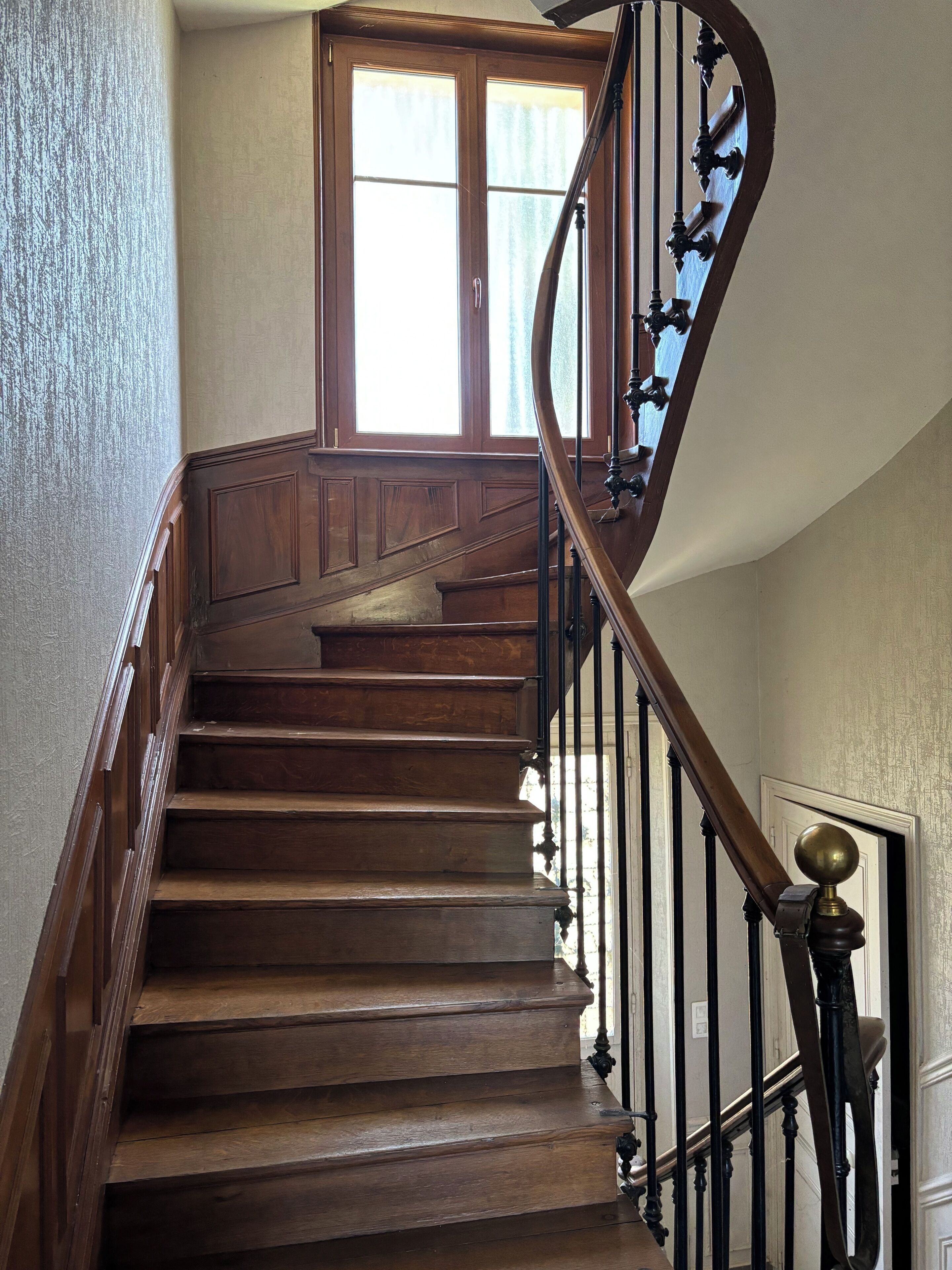 A wooden staircase with a curved handrail and a door at the top.