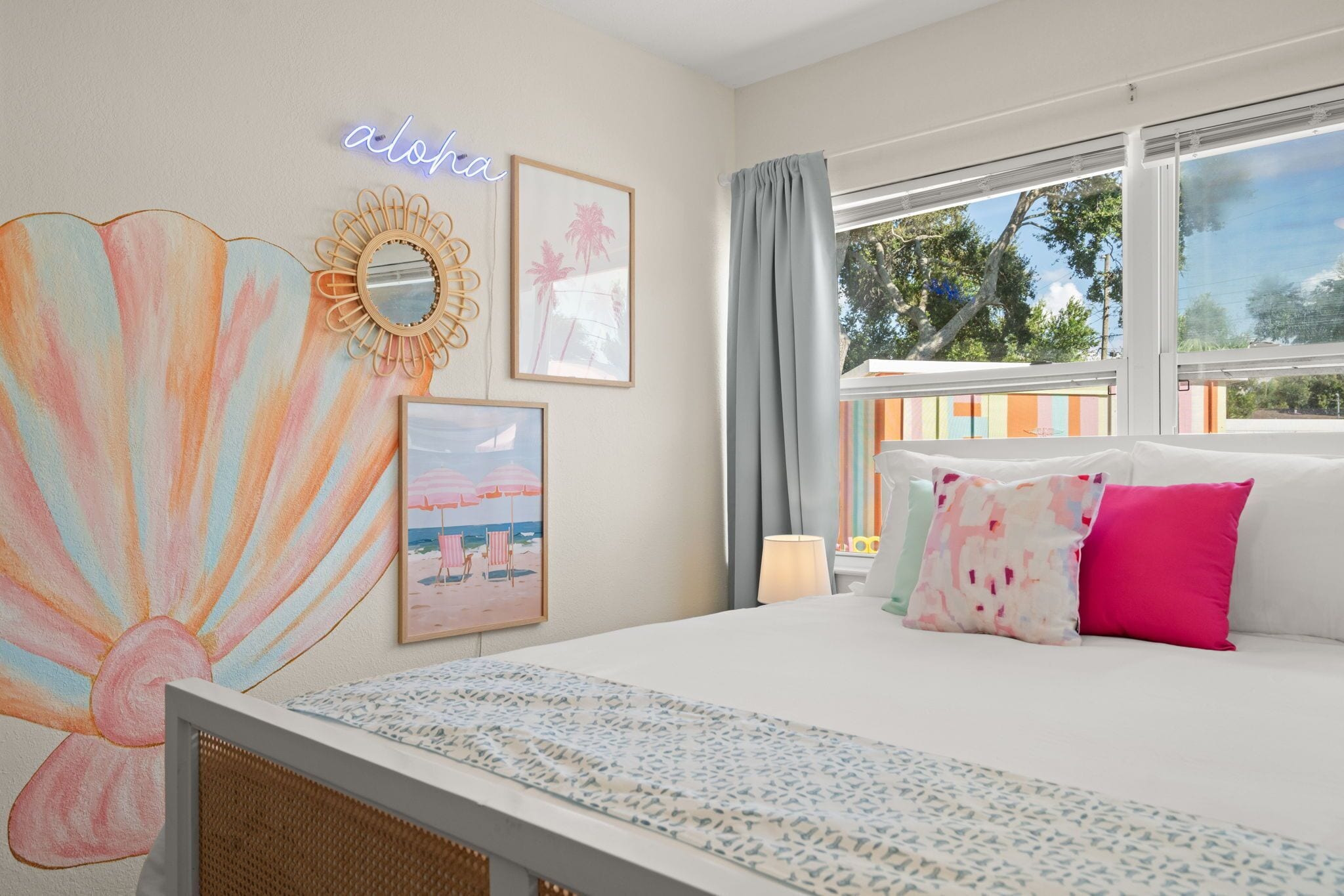Un dormitorio con cama, un ventanal grande, un letrero de neón y decoración en la pared.