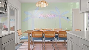 Ruokailutila, jossa on kuudelle katettu pöytä, ja pöydän ympärillä on punottuja tuoleja. Tilaa valaisee riippuvalaisin.