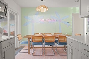 A dining area with a table set for six, surrounded by wicker chairs, under a pendant light. - Family Home Retreat•Hot Tub•Heated Pool•Mini-Golf (Seminole)