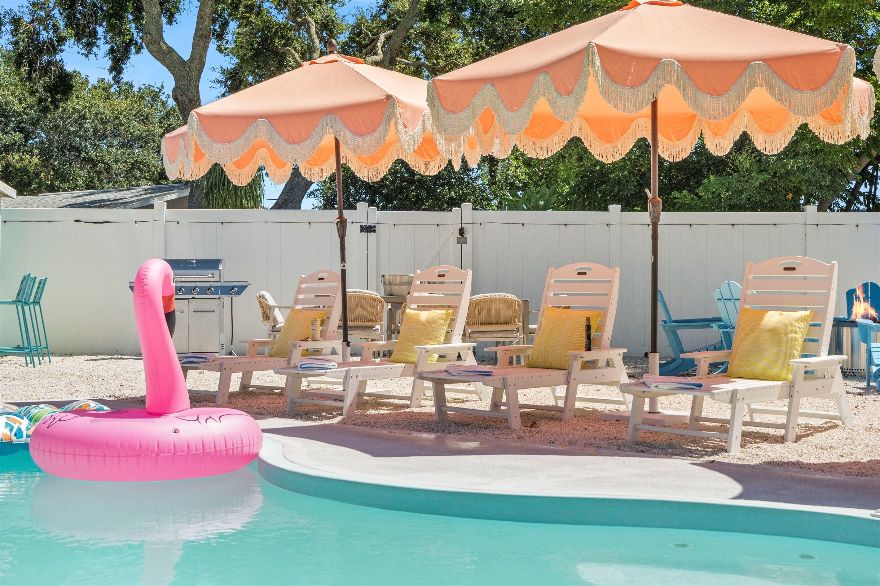 Un espace piscine avec des chaises longues et un flotteur gonflable rose.