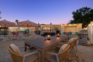 An outdoor seating area with a table and chairs, surrounded by umbrellas and string lights. - Family Home Retreat•Hot Tub•Heated Pool•Mini-Golf (Seminole)