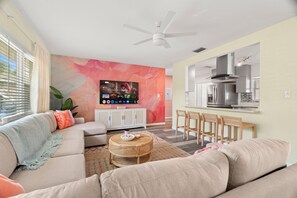 A modern living room with a sofa, a coffee table, and a TV mounted on the wall. - Heated Pool, Hot Tub, Mini-Golf • Near the Beach (Seminole)