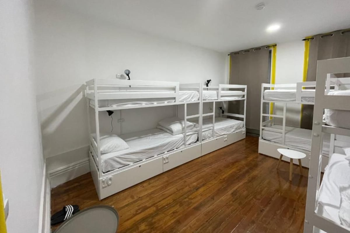 Een kamer met stapelbedden, een klein krukje en een spiegel.