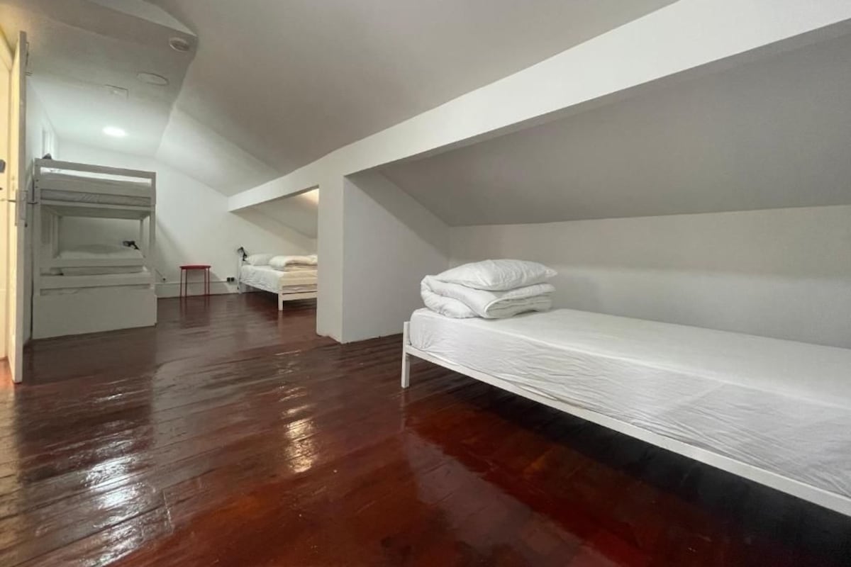 Een kamer met een stapelbed, een klein tafeltje en een stoel.