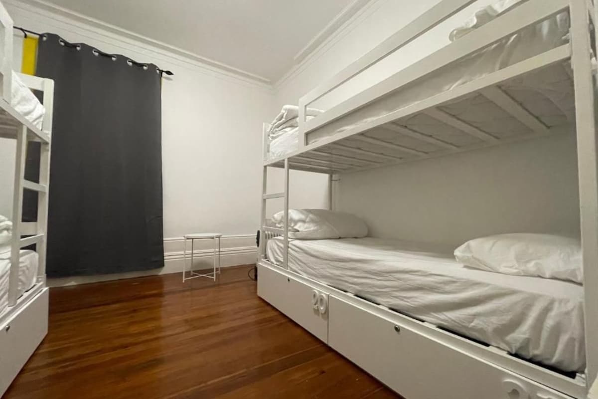 Een slaapkamer met een stapelbed, een klein tafeltje en een gordijn.