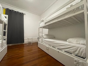 Een slaapkamer met een stapelbed, een klein tafeltje en een gordijn.