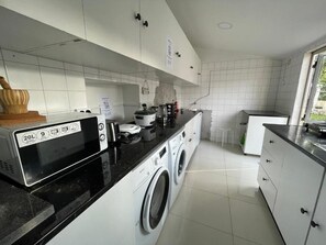 Een moderne keuken met een wasmachine, koffiezetapparaat en waterkoker op het aanrecht.
