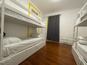 Een kamer met stapelbedden, een klein tafeltje en een gordijn.