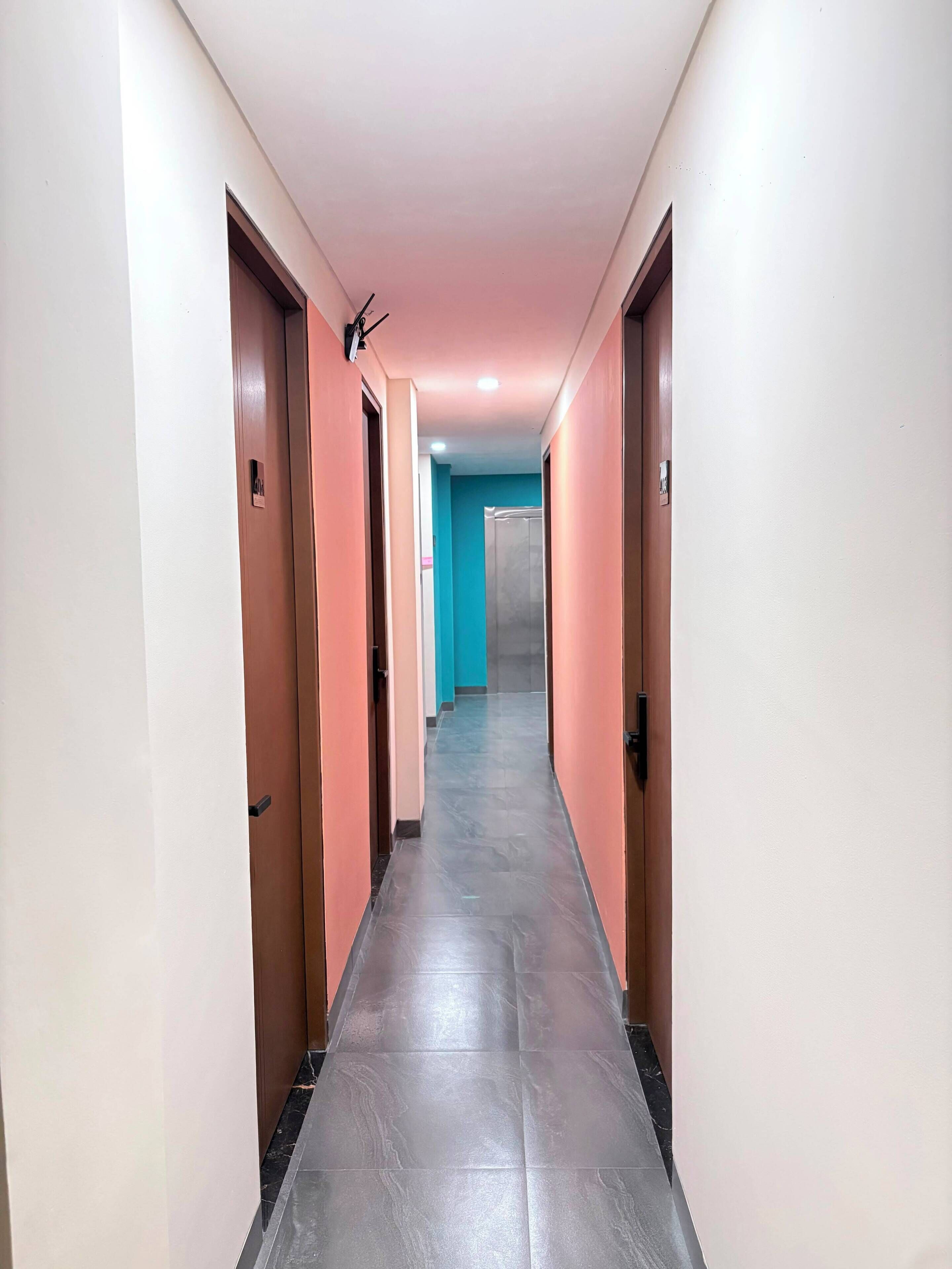 Un couloir d’hôtel avec des portes des deux côtés, un sol carrelé et un luminaire au plafond.
