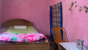 Ein Zimmer mit einem Bett, einem Stuhl, einem Tisch und einem Fenster.