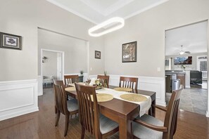 A dining room with a wooden table, chairs, and a modern pendant light. - Modern Retreat Home Near Lake Norman & Charlotte (Huntersville)