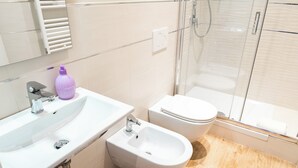 Un bagno moderno con lavandino, bidet e WC bianchi.