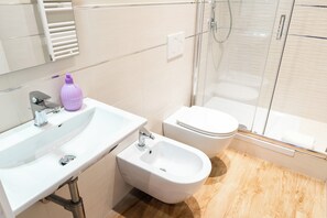 A modern bathroom with a white sink, bidet, and toilet. - Charming Guesthouse in a Central Location Comfortable Stay for Couple & Families (Roma)