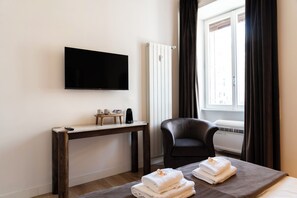 Een hotelkamer met een bed, een bureau, een stoel, een televisie en een raam met gordijnen.