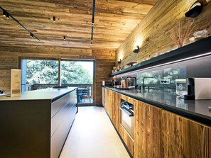 Una cuina moderna amb panells de fusta, un gran finestral i forn integrat.