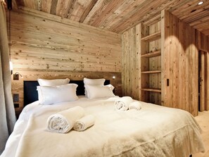 A wooden-paneled room with a bed, pillows, and a neatly made bedspread. - Elegant apartment - 8 guests (Les Allues)
