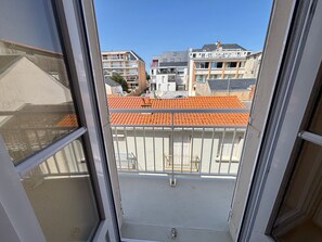 Ein Balkon mit Blick auf benachbarte Gebäude und ein Ziegeldach.