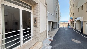 Un edificio con un cartel que dice 'Résidence du Puits Doré' y una calle estrecha que lleva a una playa.
