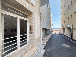 Ein Gebäude mit einem Schild, auf dem 'Résidence du Puits Doré' steht, und eine schmale Straße, die zum Strand führt.