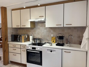 A modern kitchen with white cabinets, a microwave, a stove, and a dishwasher.