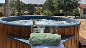 A hot tub with a bottle of champagne, glasses, and a towel.