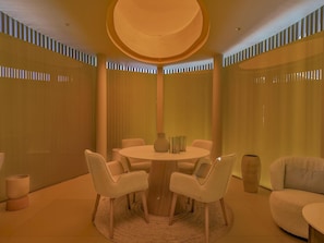 Un interior moderno con una mesa redonda, seis sillas y una columna central.