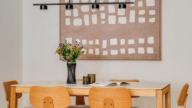 Ein Essbereich mit Tisch, Stühlen, einer Blumenvase und einem Wandbild.
