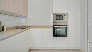 Eine moderne Küche mit weißen Schränken, einer Edelstahlspüle, einer Mikrowelle und einem Backofen.