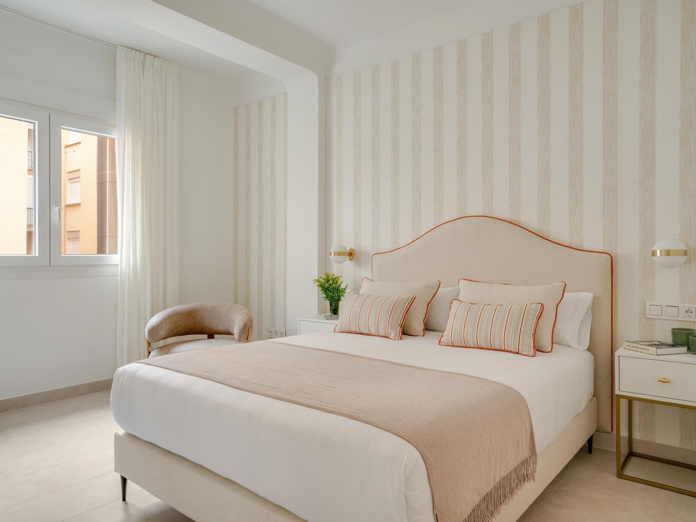 A modern bedroom with a large bed, a bedside table, a chair, and a window with curtains.