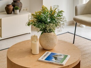 A round wooden table with a vase of flowers, two candles, and a book titled 'LE CORBUSIER'. - Stylish apartment in Soho Malaga - 6 guests (Málaga)