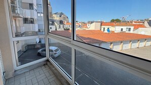 Ein Zimmer mit großem Fenster und Blick auf eine Stadtlandschaft, darunter ein Glockenturm und Gebäude mit roten Dächern.