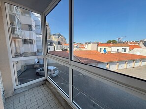 Ein Zimmer mit großem Fenster und Blick auf eine Stadtlandschaft, darunter ein Glockenturm und Gebäude mit roten Dächern.