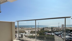 Ein Balkon mit freiem Blick auf den Strand und einen Parkplatz.
